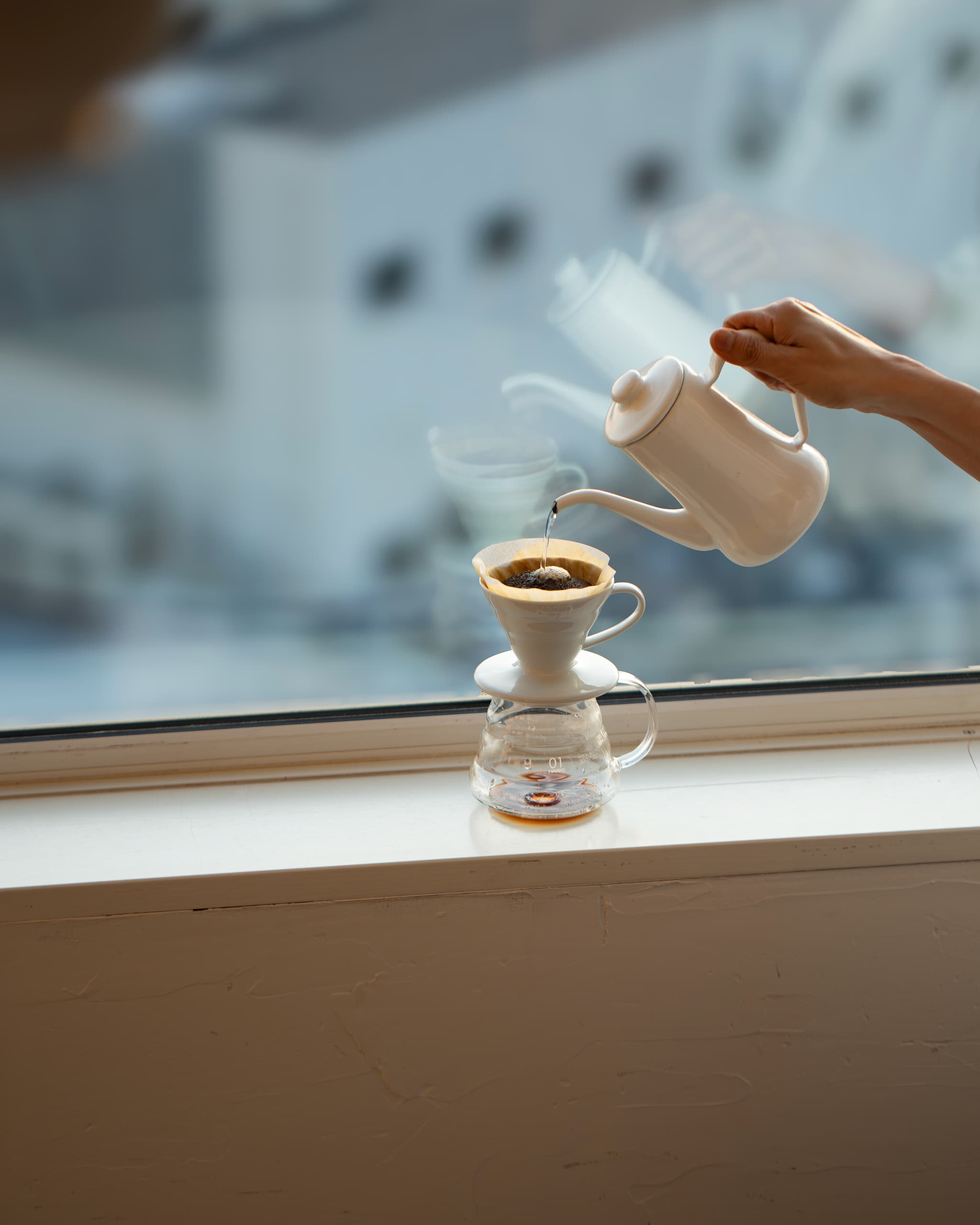 日の出直後の自然光を使った、窓辺でコーヒーをドリップする風景